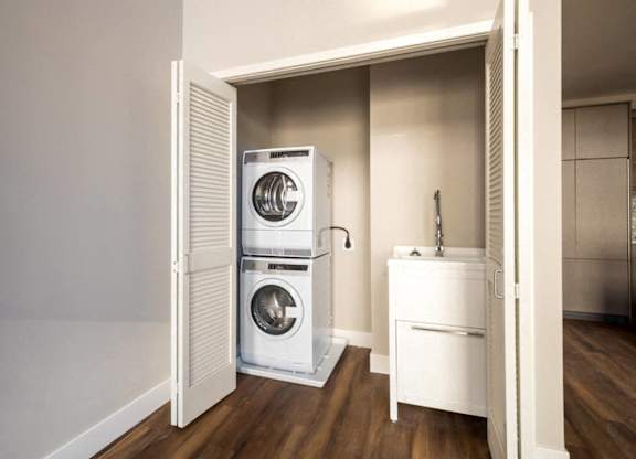 A white washing machine and dryer are stacked on top of each other in a small laundry room.