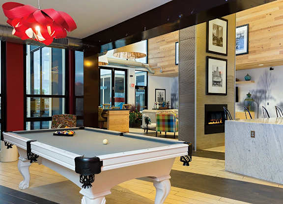 A pool table in a room with a fireplace and pictures on the wall.