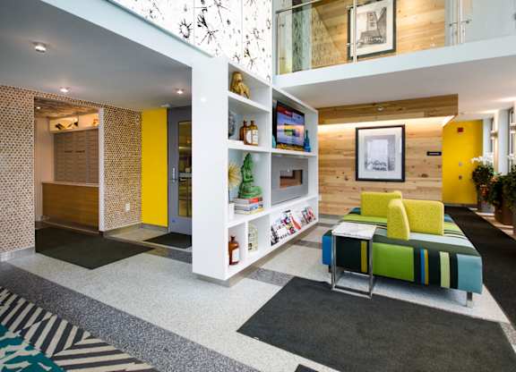 A brightly colored living room with a yellow sofa and a white bookshelf.