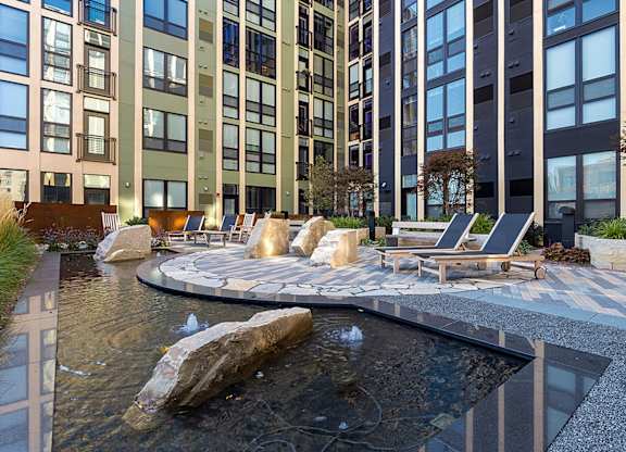 A modern outdoor seating area with a water feature in the foreground.
