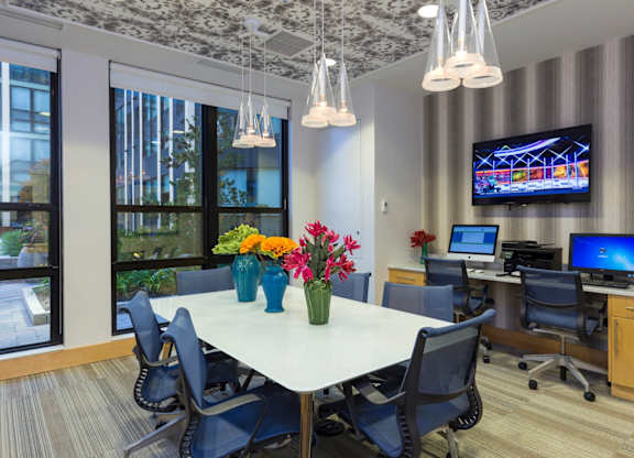 A conference room with a large table, chairs, and a television mounted on the wall.