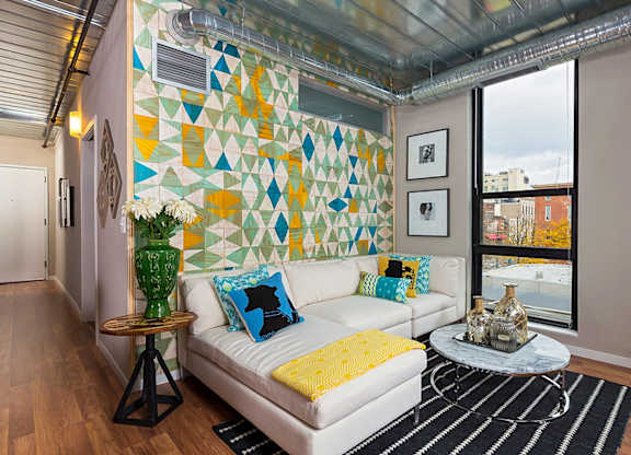 A living room with a white couch and a yellow throw pillow.