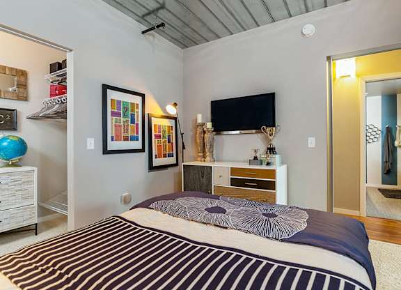 A bedroom with a bed, a television, and a mirror.