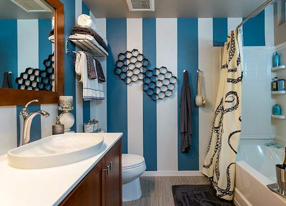 A bathroom with a white sink and a striped blue and white wall.