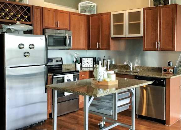 A kitchen with a stainless steel refrigerator and wooden cabinets.