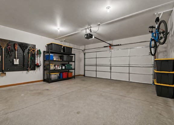 A garage with a white wall and a bicycle hanging on it.