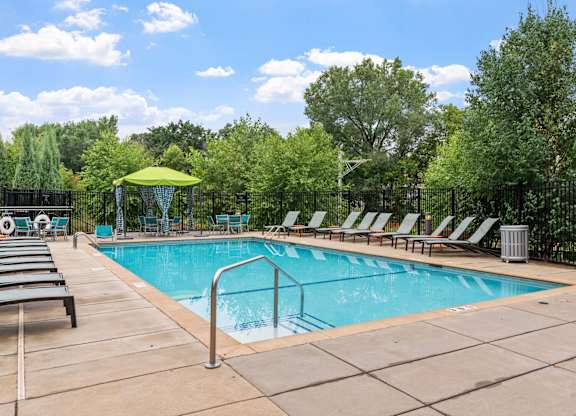 a swimming pool with chairs around it and trees in the background at Be @ Axon Green, Minnesota, 55416