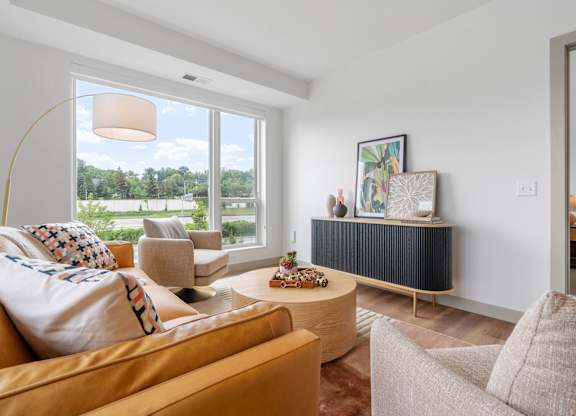 a living room with couches and chairs and a large window at The Mera, St Louis Park, MN