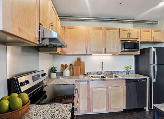 A kitchen with black appliances and wooden cabinets.