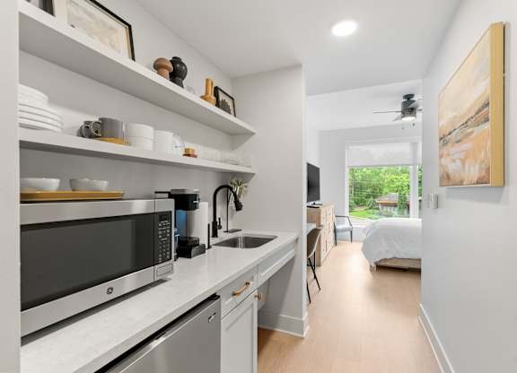 The kitchen featuring a mini fridge, microwave, sink, coffeemaker, toaster, and dishes in the Guest Suite, a reservable community amenity at Lilia in Lilydale, MN 55118