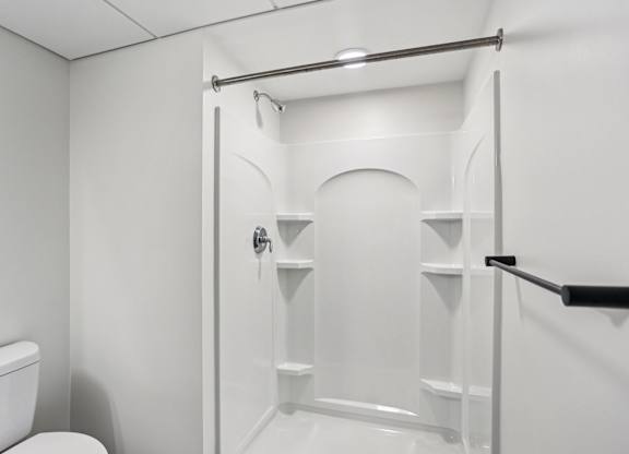 A white bathroom with a toilet and a walk-in shower.
