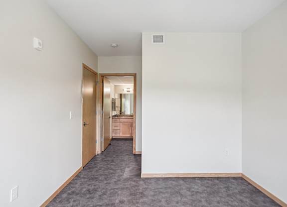 A room with a carpeted floor and a doorway leading to another room.