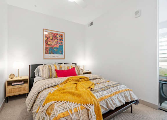 A bedroom with a bed, a nightstand with a lamp, and a framed picture on the wall. at The Mera, Minnesota, 55426