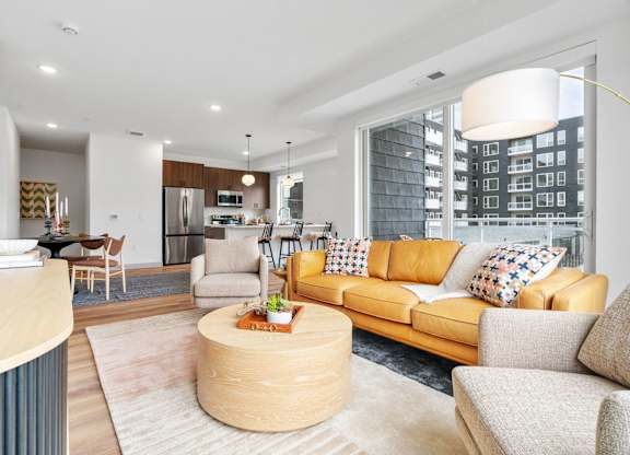 A modern living room with a yellow sofa and a wooden coffee table. at The Mera, St Louis Park, MN