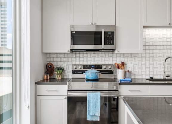 A modern kitchen with white cabinets and a blue towel hanging on the oven. at The Mera, St Louis Park, MN, 55426