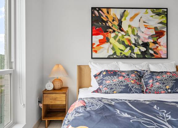 A bedroom with a large painting on the wall and a bed with a blue comforter. at The Mera, Minnesota, 55426