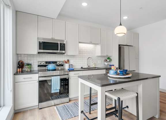 a kitchen with white cabinets and a counter top at The Mera, St Louis Park, MN