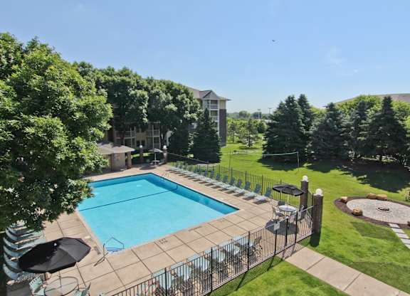 a swimming pool with a fence around it and a lawn with trees at Cityscape, St Louis Park, Minnesota