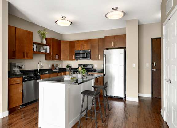 a kitchen with a large island with two stools in front of it at Be @ Axon Green, Minneapolis, MN