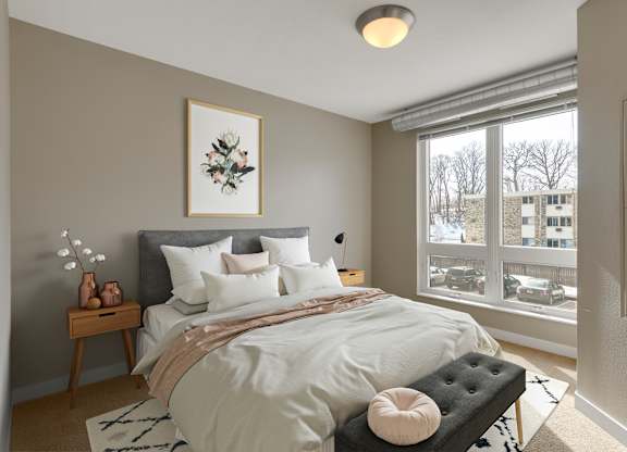 a bedroom with a large window and a bed with a white comforter and pillows at Be @ Axon Green, Minneapolis, 55416