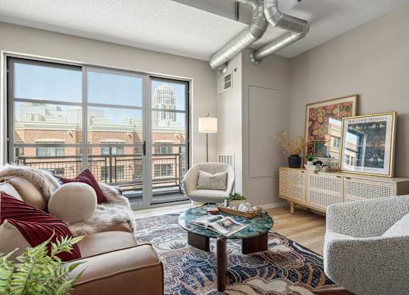 The Ellory - A living room with a brown couch, a grey chair, and a coffee table.