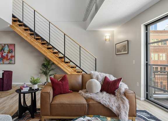 Remodeled living room at The Ellory with a brown couch and a staircase.