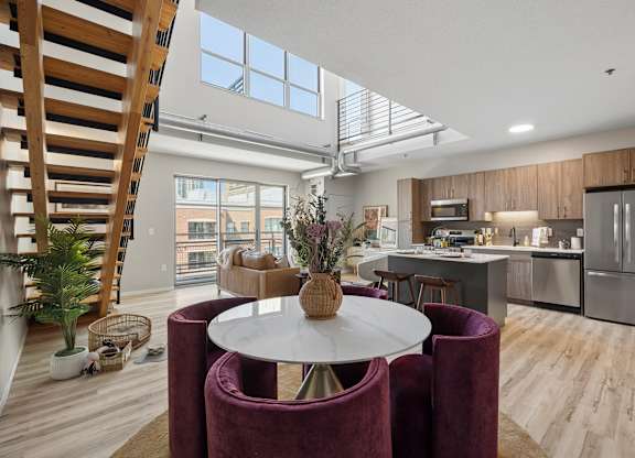 A modern kitchen at The Ellory with a dining table and chairs in the foreground and a staircase on the left.