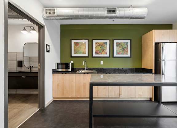 A kitchen with a green wall and a black counter top.