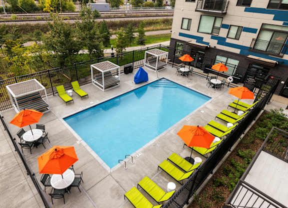 A pool surrounded by chairs and umbrellas.