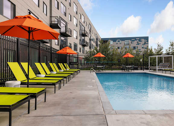 A pool surrounded by orange umbrellas and lounge chairs.