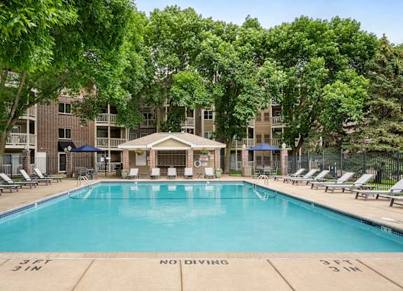a resort style pool with lounge chairs and a building in the background at Cityscape, St Louis Park, 55416