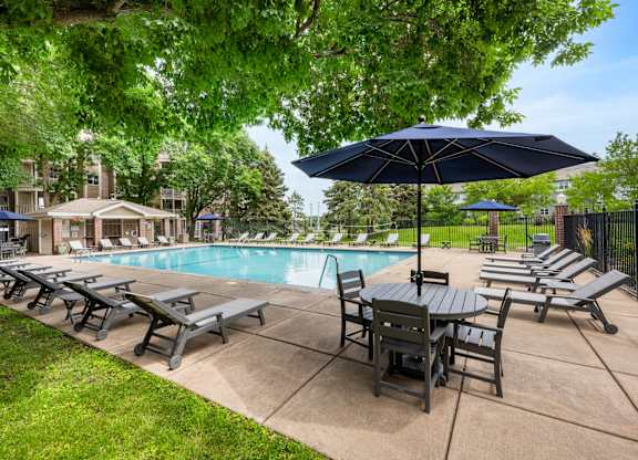 a swimming pool with patio furniture and umbrellas at Cityscape, St Louis Park, MN, 55416