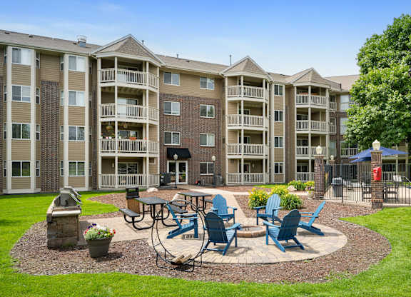 an outdoor patio with tables and chairs in front of an apartment building at Cityscape, St Louis Park, 55416