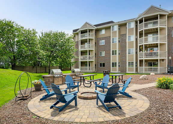 an outdoor patio with blue chairs and a fire pit at Cityscape, St Louis Park, 55416