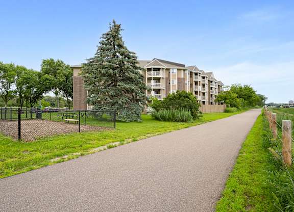 a walkway with a building in the background and a tree in the grass at Cityscape, St Louis Park, 55416