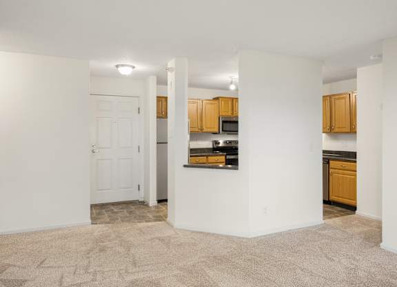 the living room and kitchen of an empty apartment with white walls and wood cabinets at Cityscape, St Louis Park, MN, 55416