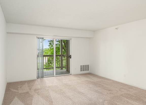 an empty living room with a sliding glass door to a balcony at Cityscape, St Louis Park, MN, 55416