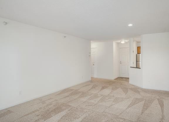 the living room and kitchen of an apartment with white walls and flooring at Cityscape, St Louis Park, 55416