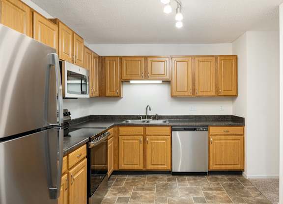 an empty kitchen with wooden cabinets and stainless steel appliances at Cityscape, St Louis Park, MN, 55416