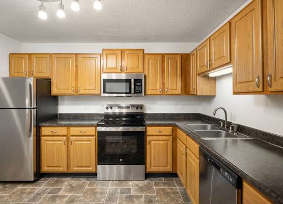 a kitchen with wooden cabinets and stainless steel appliances at Cityscape, St Louis Park, 55416