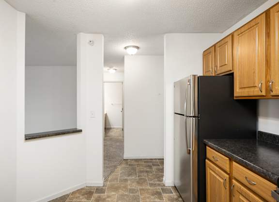 an empty kitchen with a refrigerator and wooden cabinets at Cityscape, St Louis Park, Minnesota