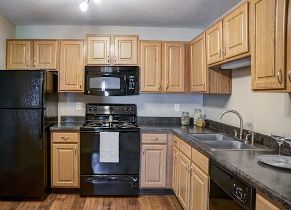 a kitchen with black appliances and wooden cabinets at Cityscape, St Louis Park, 55416