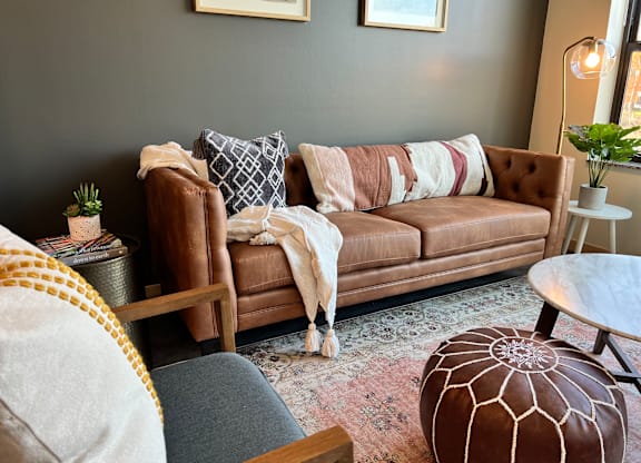 A brown couch with a blanket on it sits in a living room.