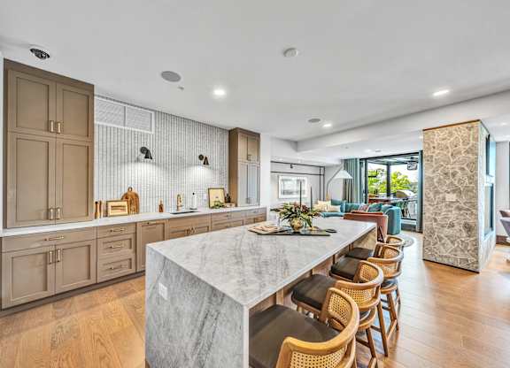 A modern kitchen with a marble countertop and wooden chairs.at Lilia, Minnesota, 55118