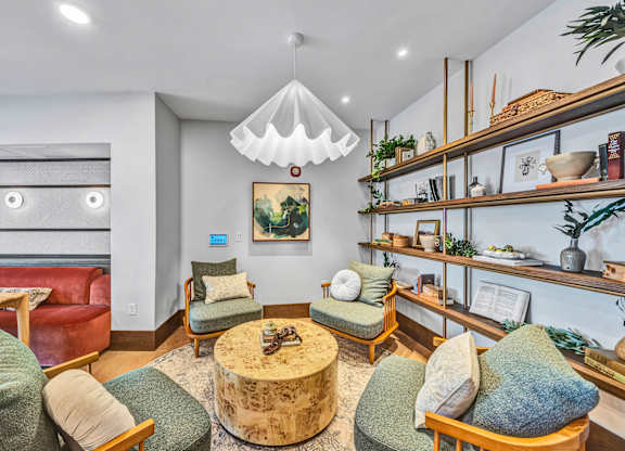 A living room with a red couch, green chairs, and a wooden coffee table. at Lilia, Lilydale, MN
