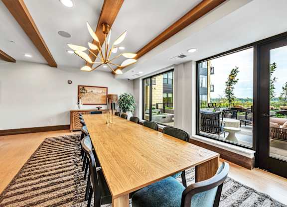 A long wooden table is surrounded by chairs in a room with a large window.at Lilia, Lilydale, MN