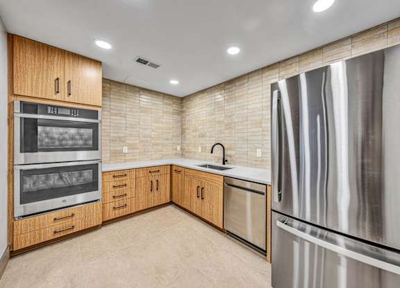 A modern kitchen with a stainless steel refrigerator and wooden cabinets.at Lilia, Minnesota, 55118