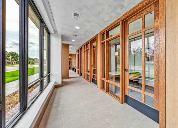 A long hallway with wood paneling and glass doors.at Lilia, Lilydale, 55118