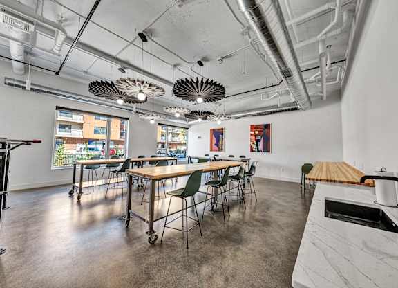 A room with a long table and chairs, a white counter, and a window with a view of a cityscape at The Mera, St Louis Park, 55426.