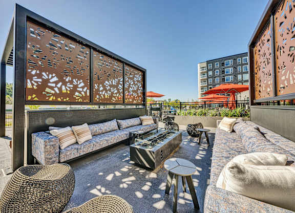 A modern outdoor seating area with a large sofa and wicker tables. at The Mera, St Louis Park, MN